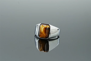 Macro shot of tiger eye stone ring with silver titanium steel band and mirror reflection