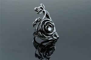 Detailed macro view of vintage silver rose ring with a clear zircon on black mirror