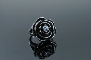 Macro shot of an oxidized silver rose ring featuring a sparkling central zircon inlay