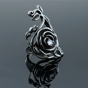 Vintage stainless steel rose ring with zircon center on reflective grey surface