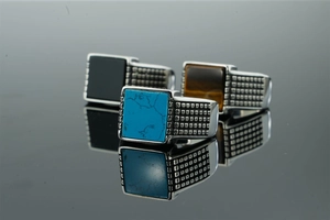 Macro detail of men's stainless steel signet rings with turquoise, tiger eye and onyx stones