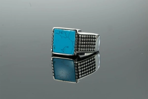 Close-up of vintage silver ring with square blue turquoise stone and side engravings