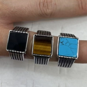 Close-up of vintage square men's rings featuring turquoise, tiger eye and onyx inlays