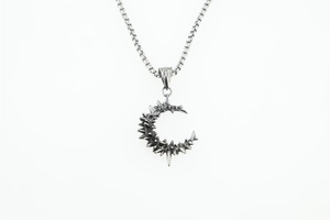 Macro detail of gothic punk crescent moon pendant with spiked design on steel chain