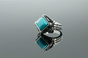 Macro detail of men's stainless steel ring featuring square turquoise stone and carvings