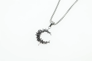 Detailed close-up of a punk-style stainless steel crescent moon pendant with thorns