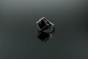 Macro shot of retro stainless steel ring with square black agate and geometric textures