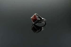 Macro shot of stainless steel ring with square reddish-brown stone and side engraving