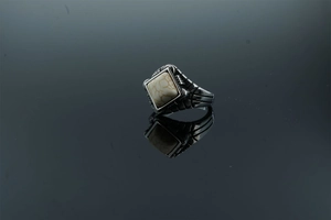 Macro shot of retro men's steel ring with white marble stone and geometric side patterns