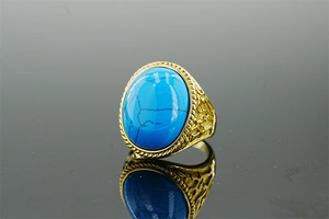 Macro shot of oval turquoise stone set in ornate gold-tone textured stainless steel band