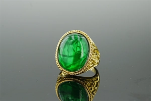 Macro shot of vintage gold ring featuring a green gemstone with gold foil texture