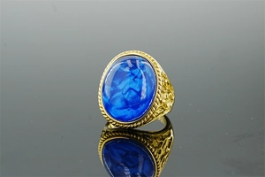 Macro shot of vintage gold stainless steel ring featuring blue oval stone with floral relief