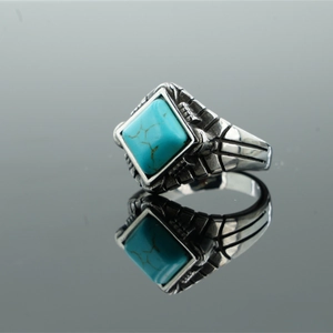 Vintage stainless steel ring with a turquoise stone inlay on a mirrored background