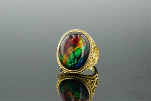 Macro shot of gold stainless steel ring with colorful ammolite stone and engraved sides