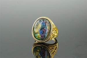 Macro detail of men's gold ring with oval iridescent stone and embossed texture