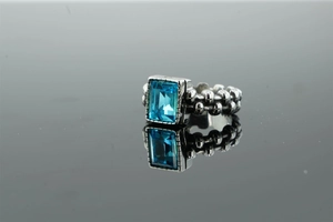 Vista macro dell'anello con gemma blu rettangolare e fascia in argento testurizzato