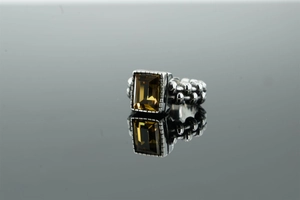 Dettaglio macro dell'anello punk retrò in acciaio con gemma gialla e trama a catena
