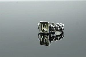 Dettaglio di un anello punk vintage con pietra verde rettangolare e maglie a forma di muso
