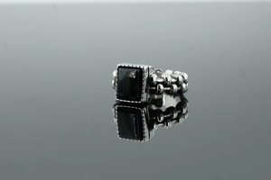 Dettaglio macro dell'anello punk in acciaio inossidabile con gemma nera rettangolare e fascia testurizzata