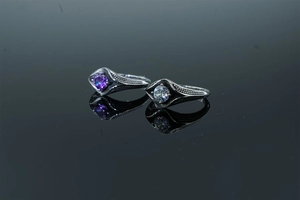 Vue macro de bagues gothiques avec zircons violets et blancs en reflet de miroir