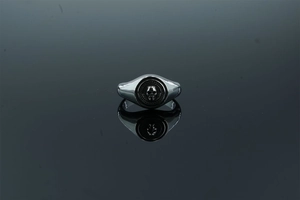 Macro view of a punk style skull ring made of polished stainless steel on a dark surface