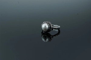 Macro view of vintage silver-tone ring with intricate textures and a center faux pearl