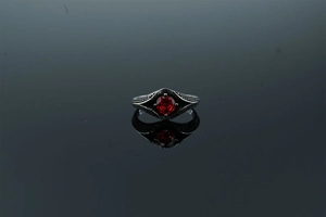 Gros plan d'une bague en acier inoxydable avec pierre rouge et motifs gravés élégants
