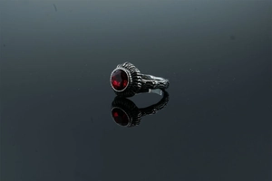 Detail of a vintage ring featuring a faceted red gemstone with a textured black band