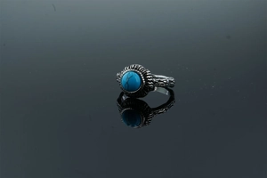 Macro detail of vintage silver ring with turquoise stone and carved texture on black mirror