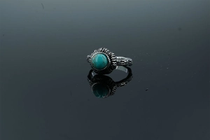 Macro detail of vintage oxidized silver ring with boho floral carvings and turquoise stone