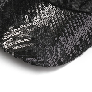 Dettaglio macro di paillettes nere e argento cucite su un cappellino in maglia