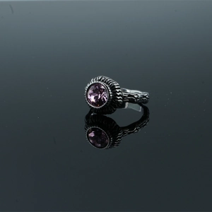 Vintage style ring with purple gemstone and antique silver textured band on mirror background
