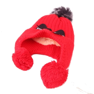 Detail of red knit kids hat with triple pom-poms, cat ears and warm fleece lining