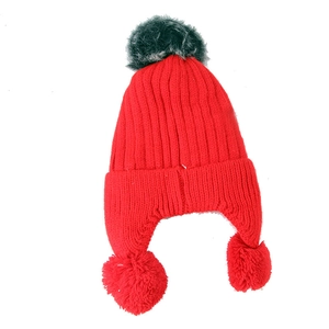 Detail of red knit earflap hat with fuzzy pom-poms and thick vertical ribbed texture