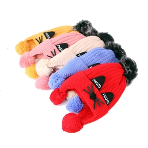 Flat lay of colorful knitted kids cat hats with ear flaps and fluffy pom-poms