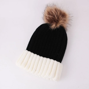 Detailed top view of a ribbed knit beanie featuring black and white contrast with a brown pompom
