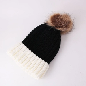 Detail of chunky knit beanie with contrast black and white stitching and faux fur pom