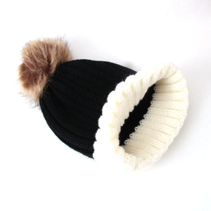 Detail of the knit texture and soft faux fur pompom on the black and white beanie