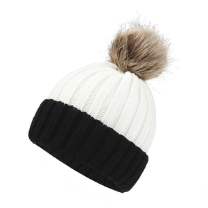 Women's warm knitted beanie featuring a black and white color block design with a brown pom-pom