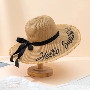 Détail de chapeau de paille avec broderie Hello Sunshine, ruban noir et bords effilochés