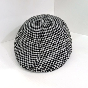 Detailed view of black and white houndstooth wool fabric on a vintage flat cap