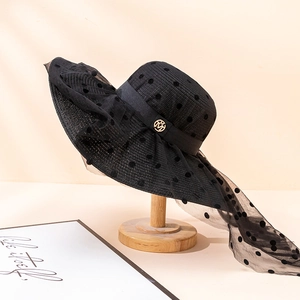 Détail du chapeau de paille à large bord avec voile en résille et emblème doré M