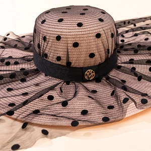 Détail d'un chapeau de paille à large bord avec tulle à pois et logo M doré chic