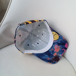 Tie-dye cotton baseball cap with graffiti prints and yellow smiley face on the brim