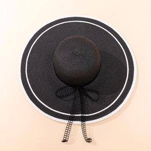 Flat lay of wide brim straw hat with black mesh lace ribbon and bow decoration