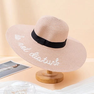 Detail of pink straw sun hat with black ribbon and do not disturb embroidery