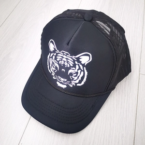 Detail of tiger print trucker cap featuring breathable mesh and curved brim on wood floor