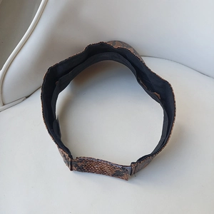 Detail view of snakeskin pattern sun visor with black lining and adjustable velcro strap
