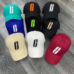 Flat lay of cotton twill baseball hats in eight colors on a dark wooden floor texture