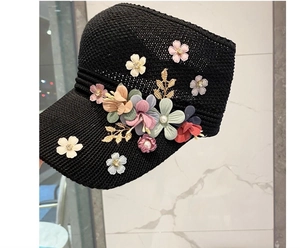 Detail of colorful fabric flowers and pearls on a black knit sun hat with gold accents